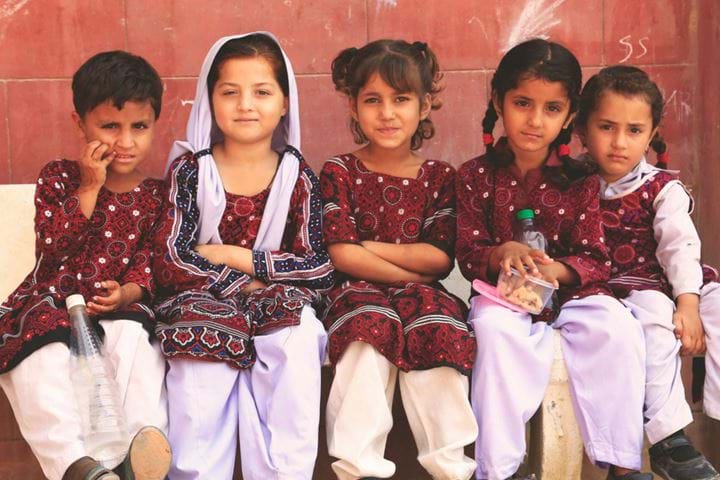 Young children sat together on bench, Pakistan