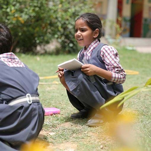 two young girls learning outside, India