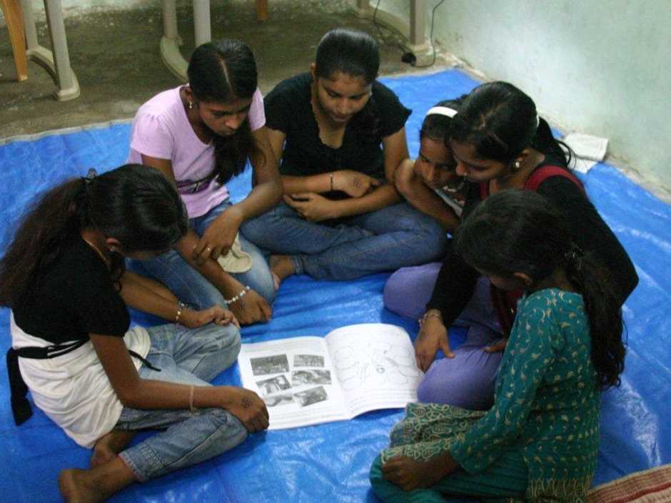 Girls sat around book, India