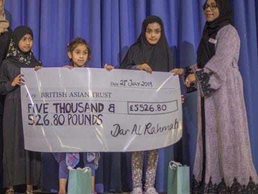 Children at school presenting large cheque after fundraising